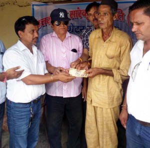 आपदा पीड़ितों को आर्थिक सहायता प्रदान करते समिति के सदस्य 